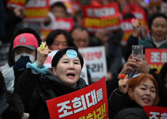 Protesters attend a rally marking the first anniversary of South Korean ousted president Yoon Suk Yeol's declaration of martial law, near the National Assembly in Seoul on December 6, 2025. (Photo by Jung Yeon-je / AFP)