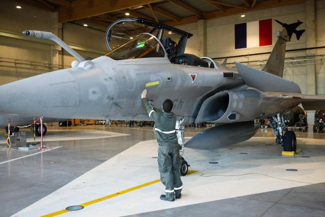 A mechanic worker of the French Air and Space Force operates around a French Air and Space Force Dassault Rafale C-5GN fighter jet displayed during a media presentation on the implementation of the National Service scheme, including an initial military training and support for young volunteers within the Air and Space Force (AAE), at the training centre of Air Base 115 in Orange, southeastern France, December 5, 2025. 600 young people will start their National Service by the end of 2026. The objective of the Air and Space Force is to have trained 2000 aviators by 2030 in the frame of this new National Service. (Photo by CLEMENT MAHOUDEAU / AFP)