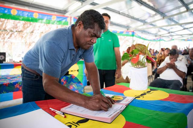Kanak pro-independence leader Christian Tein signs the party charter during the congress of the Kanak and Socialist National Liberation Front (FLNKS), New Caledonia's main pro-independence movement, in Ponerihouen, in the French overseas collectivity of New Caledonia, on December 6, 2025. (Photo by Delphine MAYEUR / AFP)