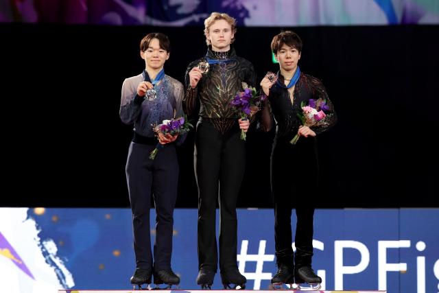 Gold medalist USA's Ilia Malinin (C), silver medalist Japan's Yuma Kagiyama (L) and bronze medalist Japan's Shun Sato pose during the award ceremony for the Senior Men Free Skating event at the ISU Grand Prix of Figure Skating final in Nagoya on December 6, 2025. (Photo by PAUL MILLER / AFP)