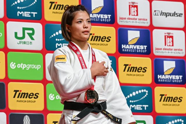 Gold medalist Japan's Uta Abe listens to the national anthem after competing in the women's under 52kg event at the Tokyo Grand Slam judo competition in Tokyo on December 6, 2025. (Photo by Toshifumi KITAMURA / AFP)