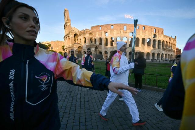 A torchbearer carries the Olympics flame during the Torch Relay to Milano Cortina 2026 Olympic Games, at the Colosseum in Rome on December 6, 2025. (Photo by Filippo MONTEFORTE / AFP)