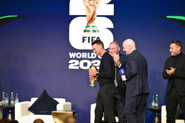 (Argentina's head coach Lionel Scaloni (L) carries the FIFA World Cup Trophy during the FIFA World Cup 2026 official match schedule announcement in Washington, DC, on December 6, 2025. (Photo by Roberto SCHMIDT / AFP)