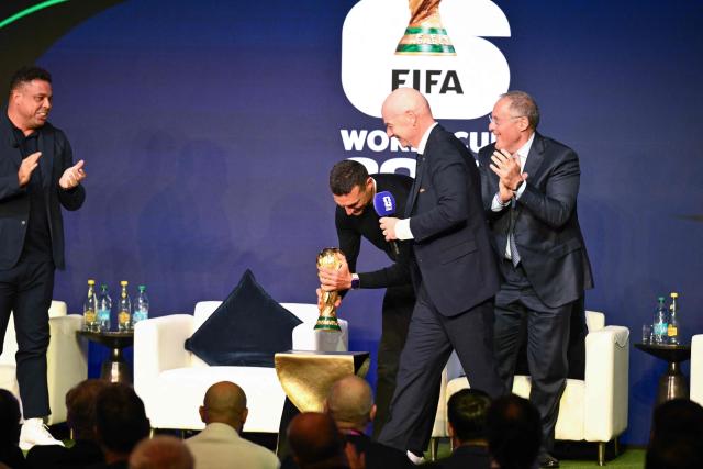 (Argentina's head coach Lionel Scaloni (2nd-L) carries the FIFA World Cup Trophy during the FIFA World Cup 2026 official match schedule announcement in Washington, DC, on December 6, 2025. (Photo by Roberto SCHMIDT / AFP)