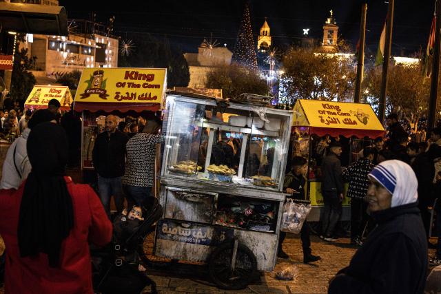 Street vendors sell snacks in Nativity Square during a Christmas tree lighting ceremony in Bethlehem, in the Israeli-occupied West Bank, on December 6, 2025. (Photo by JOHN WESSELS / AFP)