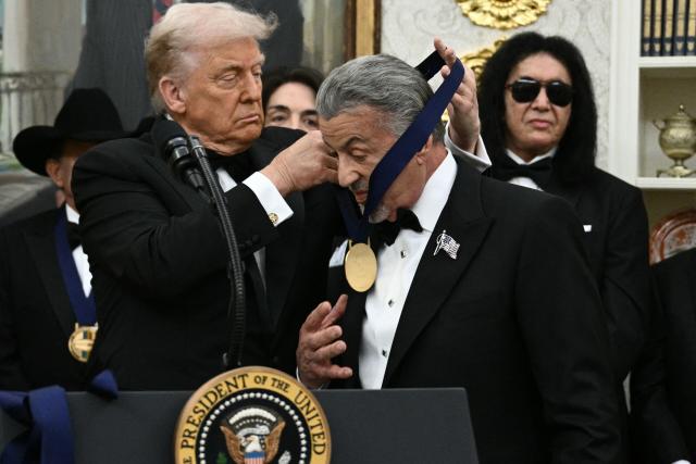 Kennedy Centre Honours recipient actor Sylvester Stallone receives a medal from US President Donald Trump during the Kennedy Centre Honours medal presentation ahead of tomorrow's ceremony, in the Oval Office of the White House in Washington, DC, December 6, 2025. (Photo by Brendan SMIALOWSKI / AFP)