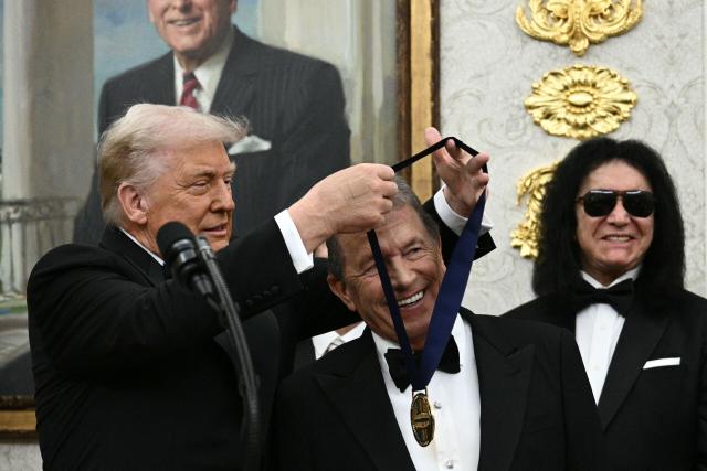 Kennedy Centre Honours recipient Broadway actor Michael Crawford receives a medal from US President Donald Trump during the Kennedy Centre Honours medal presentation ahead of tomorrow's ceremony, in the Oval Office of the White House in Washington, DC, December 6, 2025. (Photo by Brendan SMIALOWSKI / AFP)