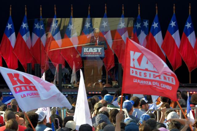 Chilean presidential candidate Jose Antonio Kast (C) of the Republican Party delivers a speech behind bulletproof glass during his closing campaign rally in Concepcion, Chile, on December 6, 2025. Chile will choose its next president in a runoff on December 14, with far-right candidate Jose Antonio Kast as the clear favorite against leftist Jeannette Jara, after a campaign marked by fears over crime and irregular migrants. (Photo by GUILLERMO SALGADO / AFP)