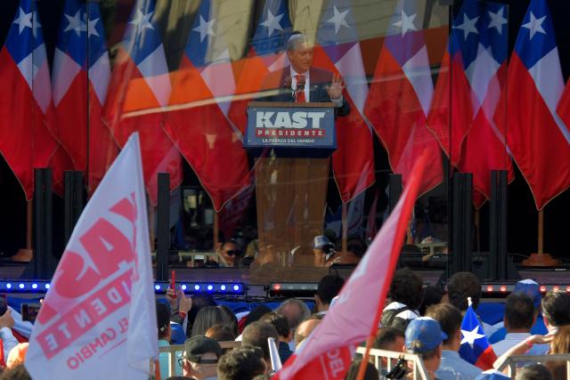 Chilean presidential candidate Jose Antonio Kast (C) of the Republican Party delivers a speech behind bulletproof glass during his closing campaign rally in Concepcion, Chile, on December 6, 2025. Chile will choose its next president in a runoff on December 14, with far-right candidate Jose Antonio Kast as the clear favorite against leftist Jeannette Jara, after a campaign marked by fears over crime and irregular migrants. (Photo by GUILLERMO SALGADO / AFP)