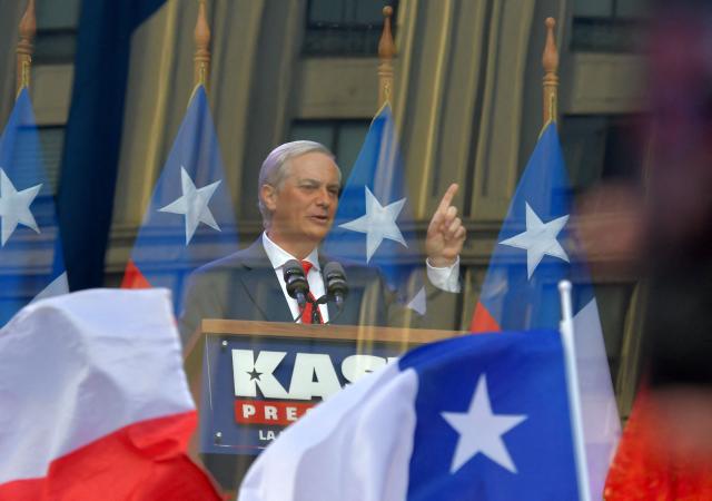 Chilean presidential candidate Jose Antonio Kast (C) of the Republican Party delivers a speech behind bulletproof glass during his closing campaign rally in Concepcion, Chile, on December 6, 2025. Chile will choose its next president in a runoff on December 14, with far-right candidate Jose Antonio Kast as the clear favorite against leftist Jeannette Jara, after a campaign marked by fears over crime and irregular migrants. (Photo by GUILLERMO SALGADO / AFP)