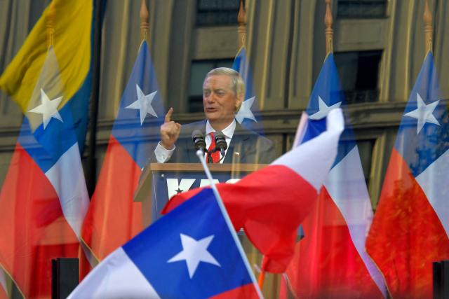 Chilean presidential candidate Jose Antonio Kast (C) of the Republican Party delivers a speech behind bulletproof glass during his closing campaign rally in Concepcion, Chile, on December 6, 2025. Chile will choose its next president in a runoff on December 14, with far-right candidate Jose Antonio Kast as the clear favorite against leftist Jeannette Jara, after a campaign marked by fears over crime and irregular migrants. (Photo by GUILLERMO SALGADO / AFP)