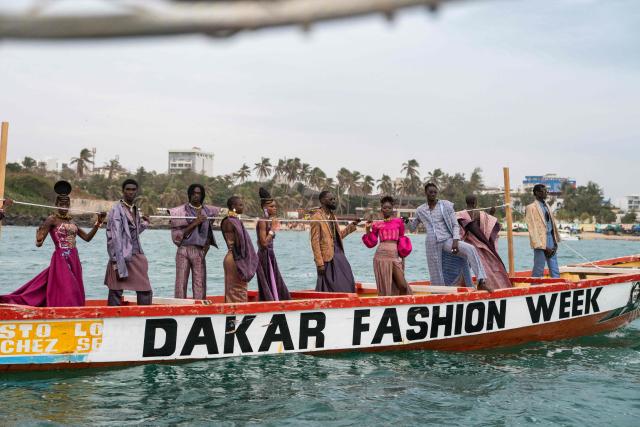 Models, wearing designs by "Loulou Design" collection, ride on a pirogue during the final show of the Dakar Fashion Week in Ngor Bay, Dakar, Senegal, on December 6, 2025. (Photo by NICOLAS REMENE / AFP)