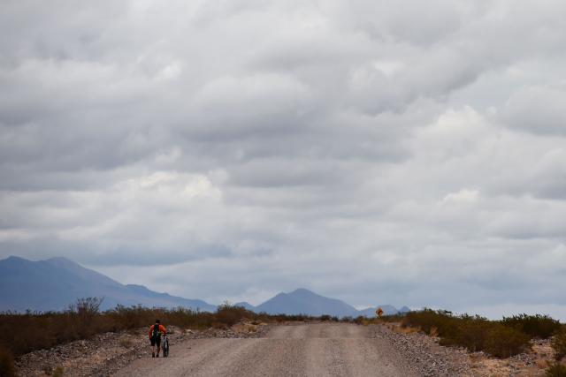 A man walks with his bike on National Route 147 toward Uspallata, which connects with the town of Barreal in San Juan Province, Mendoza, Argentina, on December 6, 2025. (Photo by Andres Larrovere / AFP)