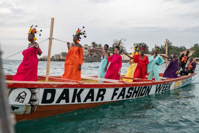 Models, wearing designs by Senegalese fashion designer Adama Paris, ride on a pirogue during the final show of the Dakar Fashion Week in Ngor Bay, Dakar, Senegal, on December 6, 2025. (Photo by NICOLAS REMENE / AFP)