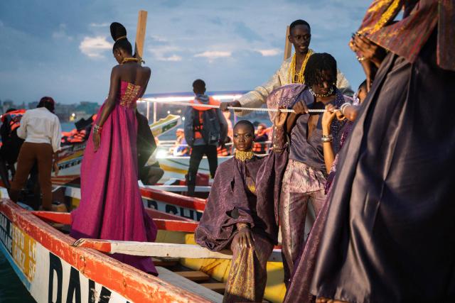 Models, wearing designs by "Loulou Design" collection, ride on a pirogue during the final show of the Dakar Fashion Week in Ngor Bay, Dakar, Senegal, on December 6, 2025. (Photo by NICOLAS REMENE / AFP)