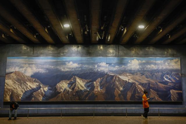 A young man walks past a painting at La Moneda metro station in Santiago, eight days before the presidential runoff election, on December 6, 2025. Chile will choose its next president in a runoff on December 14, with far-right candidate Jose Antonio Kast as the clear favorite against leftist Jeannette Jara, after a campaign marked by fears over crime and irregular migrants. (Photo by Raul BRAVO / AFP)