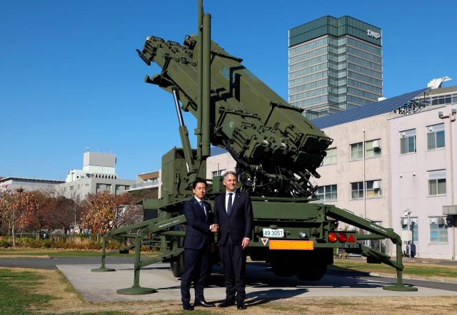 Japanese Defence Minister Shinjiro Koizumi (L) poses with Australian Defence Minister Richard Marles in front of a Patriot Advanced Capability-3 (PAC-3) missile interceptor unit at the Defense Ministry in Tokyo on December 7, 2025. (Photo by Franck ROBICHON / POOL / AFP)