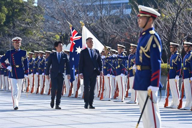 Japan’s Defence Minister Shinjiro Koizumi (L) and Australia’s Defence Minister Richard Marles review honour guards during a welcome ceremony at the Ministry of Defense in Tokyo on December 7, 2025. (Photo by David Mareuil / POOL / AFP)