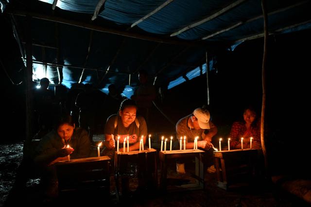 Relatives of the victims hold a vigil following a boat accident at the port of Iparia, in the Ucayali department of Peru’s central jungle, on December 6, 2025. At least 12 people, including three children, died on December 1, 2025, when a landslide sank two boats docked at a river port in central Peru, with dozens of others missing, officials said. (Photo by Hugo Alejos / AFP)