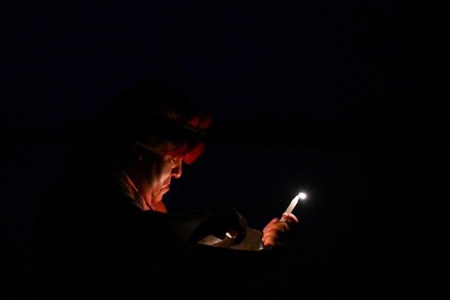 TOPSHOT - An Achuar indigenous man performs an offering ceremony to the Ucayali River, asking it to release and allow the bodies of the victims to be found at the port of Iparia, in the Ucayali department of Peru’s central jungle, on December 6, 2025. At least 12 people, including three children, died on December 1, 2025, when a landslide sank two boats docked at a river port in central Peru, with dozens of others missing, officials said. (Photo by Hugo Alejos / AFP)