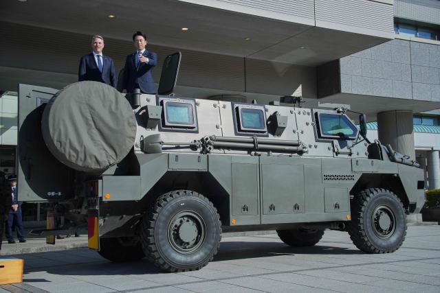 Japan’s Defence Minister Shinjiro Koizumi (R) and Australia’s Defence Minister Richard Marles pose in an Australian-made Bushmaster Mine Resistant Ambush Protected (MRAP) vehicle ahead of a bilateral meeting at the Ministry of Defense in Tokyo on December 7, 2025. (Photo by Eugene Hoshiko / POOL / AFP)