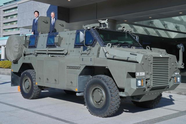 Japan’s Defence Minister Shinjiro Koizumi (L) and Australia’s Defence Minister Richard Marles ride pose in an Australian-made Bushmaster Mine Resistant Ambush Protected (MRAP) vehicle ahead of a bilateral meeting at the Ministry of Defense in Tokyo on December 7, 2025. (Photo by Eugene Hoshiko / POOL / AFP)