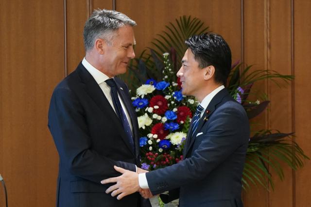 Japan’s Defence Minister Shinjiro Koizumi (R) and Australia’s Defence Minister Richard Marles shake hands after a press conference at the Ministry of Defence in Tokyo on December 7, 2025. (Photo by Kazuhiro NOGI / POOL / AFP)