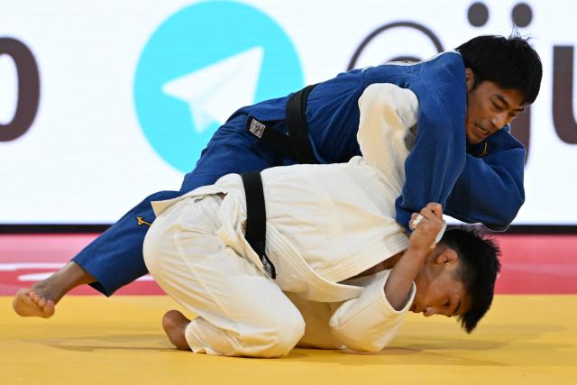 Japan's Taiki Nakamura (white) and Taiwan's Yang Yung Wei (blue) compete in the men's -60kg category quarter-final match at the Tokyo Grand Slam judo competition in Tokyo on December 7, 2025. (Photo by Toshifumi KITAMURA / AFP)