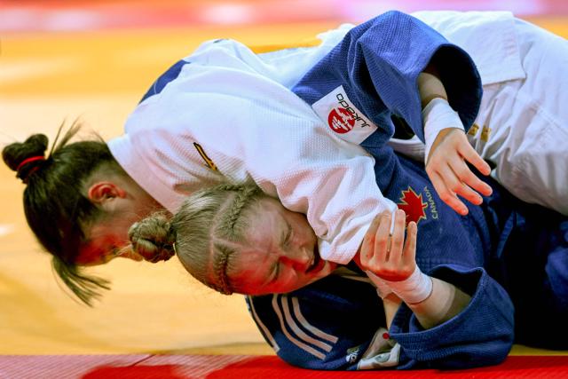 Japan's Kurena Ikeda (white) and Canada's Coralie Godbout (blue) compete in the women's -78kg category quarter-final match at the Tokyo Grand Slam judo competition in Tokyo on December 7, 2025. (Photo by Toshifumi KITAMURA / AFP)