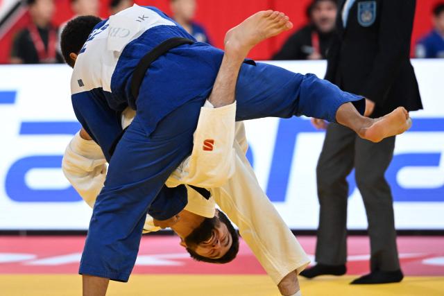 Tajikistan's Obid Dzhebov (white) and France's Daikii Bouba (blue) compete in the men's -66kg category repechage match at the Tokyo Grand Slam judo competition in Tokyo on December 7, 2025. (Photo by Toshifumi KITAMURA / AFP)