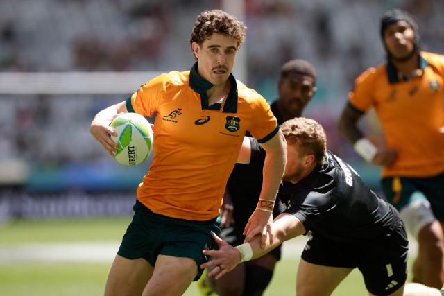 TOPSHOT - Australia's Ben Dowling runs with the ball to score a try during the 5th place Semi Final HSBC World Rugby Sevens Series men's rugby match between New Zealand and Australia at the DHL stadium in Cape Town on December 7, 2025. (Photo by GIANLUIGI GUERCIA / AFP)