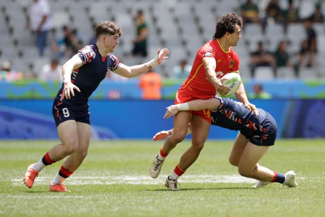 Spain's Eduardo Lopez passes the ball as he is tackled during the 5th place Semi Final HSBC World Rugby Sevens Series men's rugby match between Spain and Great Britain at the DHL stadium in Cape Town on December 7, 2025. (Photo by GIANLUIGI GUERCIA / AFP)