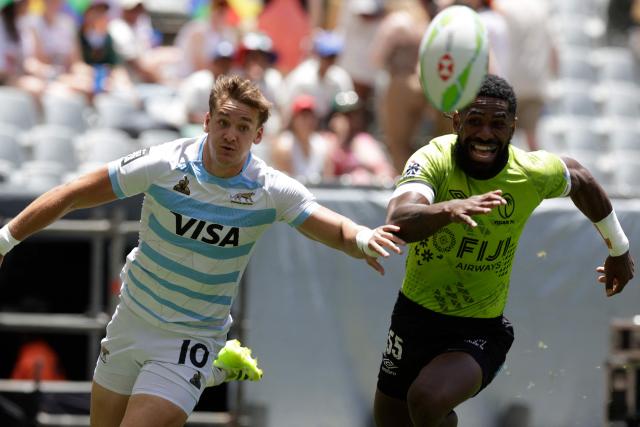 Argentina's Santiago Mare (L) and Fiji's George Bose (R) chase the ball during the Semi Final HSBC World Rugby Sevens Series men's rugby match between Argentina and Fiji at the DHL stadium in Cape Town on December 7, 2025. (Photo by GIANLUIGI GUERCIA / AFP)