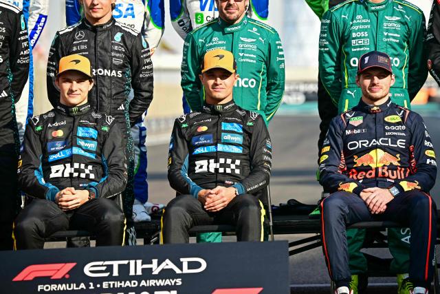 (L-R) McLaren's Australian driver Oscar Piastri, McLaren's British driver Lando Norris and Red Bull Racing's Dutch driver Max Verstappen pose for a group photo with other drivers ahead of the Abu Dhabi Formula One Grand Prix at the Yas Marina Circuit in Abu Dhabi on December 7, 2025. (Photo by Giuseppe CACACE / AFP)