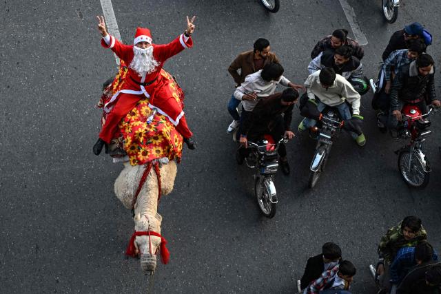 A Christian devotee dressed as Santa Claus rides a camel during a rally ahead of Christmas celebrations in Islamabad on December 7, 2025. (Photo by Aamir QURESHI / AFP)