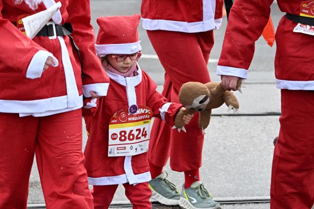 A young participant wearing a Santa Claus costume takes part in the traditional Santa Claus run close to the Danube River in Budapest, Hungary, on December 7, 2025. Around five thousand participants took part in the run for three categories: families with children, amateurs and professional runners. (Photo by Attila KISBENEDEK / AFP)
