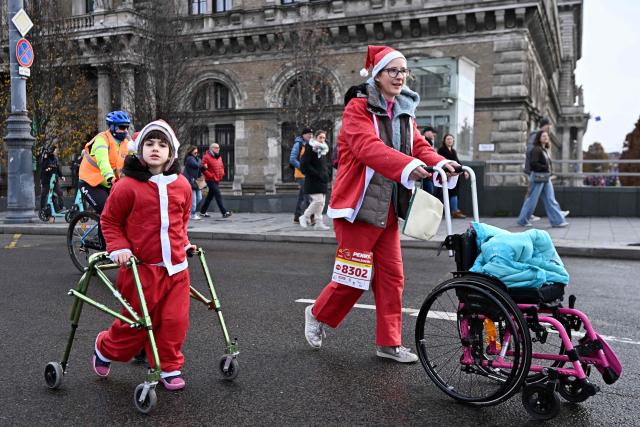 A young participant wearing a Santa Claus costume takes part in the traditional Santa Claus run close to the Danube River in Budapest, Hungary, on December 7, 2025. Around five thousand participants took part in the run for three categories: families with children, amateurs and professional runners. (Photo by Attila KISBENEDEK / AFP)