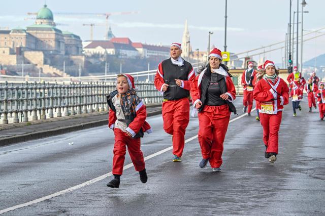 A family in Santa Claus costumes takes part in the traditional Santa Claus run close to the Danube River in Budapest, Hungary, on December 7, 2025. Around five thousand participants took part in the run for three categories: families with children, amateurs and professional runners. (Photo by Attila KISBENEDEK / AFP)