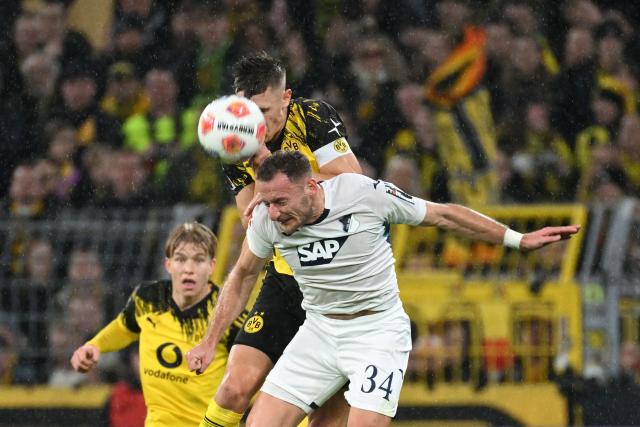 Dortmund's German defender #04 Nico Schlotterbeck (C) and Hoffenheim's Czech midfielder #34 Vladimir Coufal (R, bottom) vie for a header during the German first division Bundesliga football match between BVB Borussia Dortmund and TSG 1899 Hoffenheim in Dortmund, western Germany, on December 7, 2025. (Photo by UWE KRAFT / AFP) / DFL REGULATIONS PROHIBIT ANY USE OF PHOTOGRAPHS AS IMAGE SEQUENCES AND/OR QUASI-VIDEO