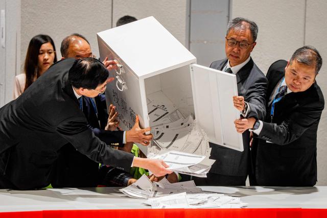 Secretary for Constitutional and Mainland Affairs Erick Tsang Kwok-wai (2L) helps empty the first ballot box after polls closed in the Legislative Council elections in Hong Kong, China, on December 7, 2025. (Photo by Leung Man Hei / AFP)