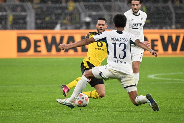 Dortmund's Brazilian defender #02 Yan Couto (L) and Hoffenheim's Brazilian defender #13 Bernardo (C) vie for the ball during the German first division Bundesliga football match between BVB Borussia Dortmund and TSG 1899 Hoffenheim in Dortmund, western Germany, on December 7, 2025. (Photo by UWE KRAFT / AFP) / DFL REGULATIONS PROHIBIT ANY USE OF PHOTOGRAPHS AS IMAGE SEQUENCES AND/OR QUASI-VIDEO