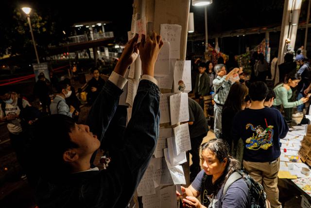 People pay their respects for the victims of a deadly fire at the Wang Fuk Court residential estate in Tai Po district of Hong Kong on December 7, 2025. (Photo by Leung Man Hei / AFP)