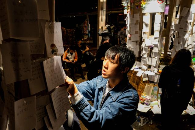 People pay their respects for the victims of a deadly fire at the Wang Fuk Court residential estate in Tai Po district of Hong Kong on December 7, 2025. (Photo by Leung Man Hei / AFP)