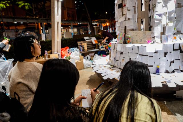 People pay their respects for the victims of a deadly fire at the Wang Fuk Court residential estate in Tai Po district of Hong Kong on December 7, 2025. (Photo by Leung Man Hei / AFP)