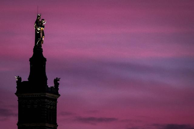 TOPSHOT - This photograph taken on December 7, 2025 the newly restored statue of the Virgin Mary atop the Basilica of Notre-Dame de la Garde, known to the people of Marseille as Bonne Mere, at sunset, in Marseille, southern France. (Photo by Thibaud MORITZ / AFP)