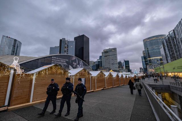 French Republican Security Corps (CRS - Compagnies Republicaines de Securite) police officers patrol around the Christmas market on the Parvis de La Defense, in the business district of La Defense, in Puteaux outside Paris, on December 7, 2025. (Photo by Ian LANGSDON / AFP)