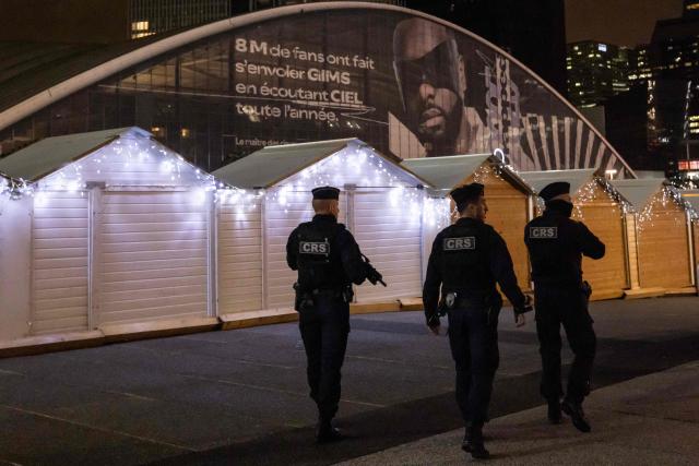 French Republican Security Corps (CRS - Compagnies Republicaines de Securite) police officers patrol around the Christmas market on the Parvis de La Defense, in the business district of La Defense, in Puteaux outside Paris, on December 7, 2025. (Photo by Ian LANGSDON / AFP)
