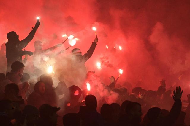 Lorient’s supporters hold smoke flares as they cheer for their team during the French L1 football match between FC Lorient and Olympique Lyonnais (OL) at the Stade du Moustoir stadium in Lorient, western France, on December 7, 2025. (Photo by Damien Meyer / AFP)