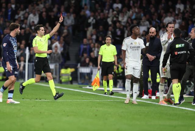 Referee Alejandro Quintero shows a red card to Real Madrid's Spanish defender #18 Alvaro Carreras (R) during the Spanish league football match between Real Madrid CF and RC Celta de Vigo at the Santiago Bernabeu Stadium in Madrid on December 7, 2025. (Photo by Thomas COEX / AFP)