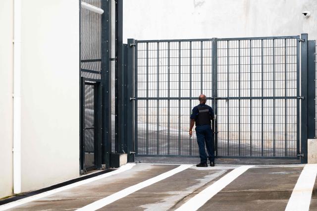 A penitentiary administration officer stands next to a gate at the new detention center of Basse-Terre in the French archipelago of Guadeloupe, on December 7, 2025. The French Minister of Justice inaugurated on December 7, 2025 in Basse-Terre, the prefecture of the Guadeloupe archipelago, the new detention center that had been under construction for several years. (Photo by Carla Bernhardt / AFP)